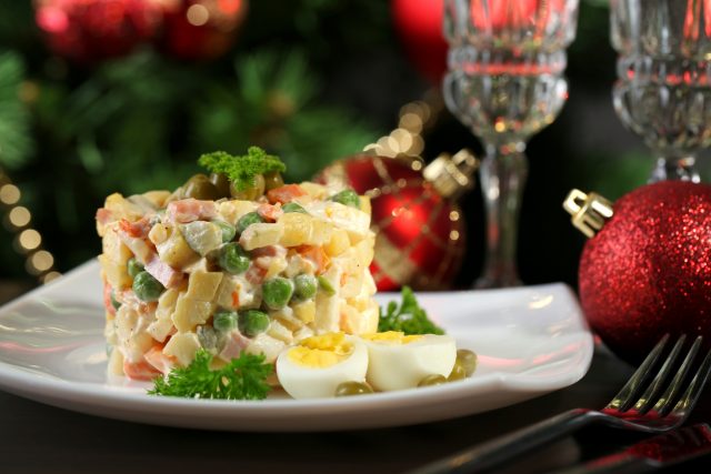 Russian traditional salad Olivier, on wooden table, on bright background